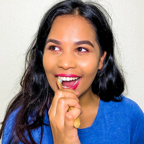 Woman brushing teeth with bamboo toothbrush
