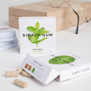 Simply Gum packaging with gum pieces on a light surface