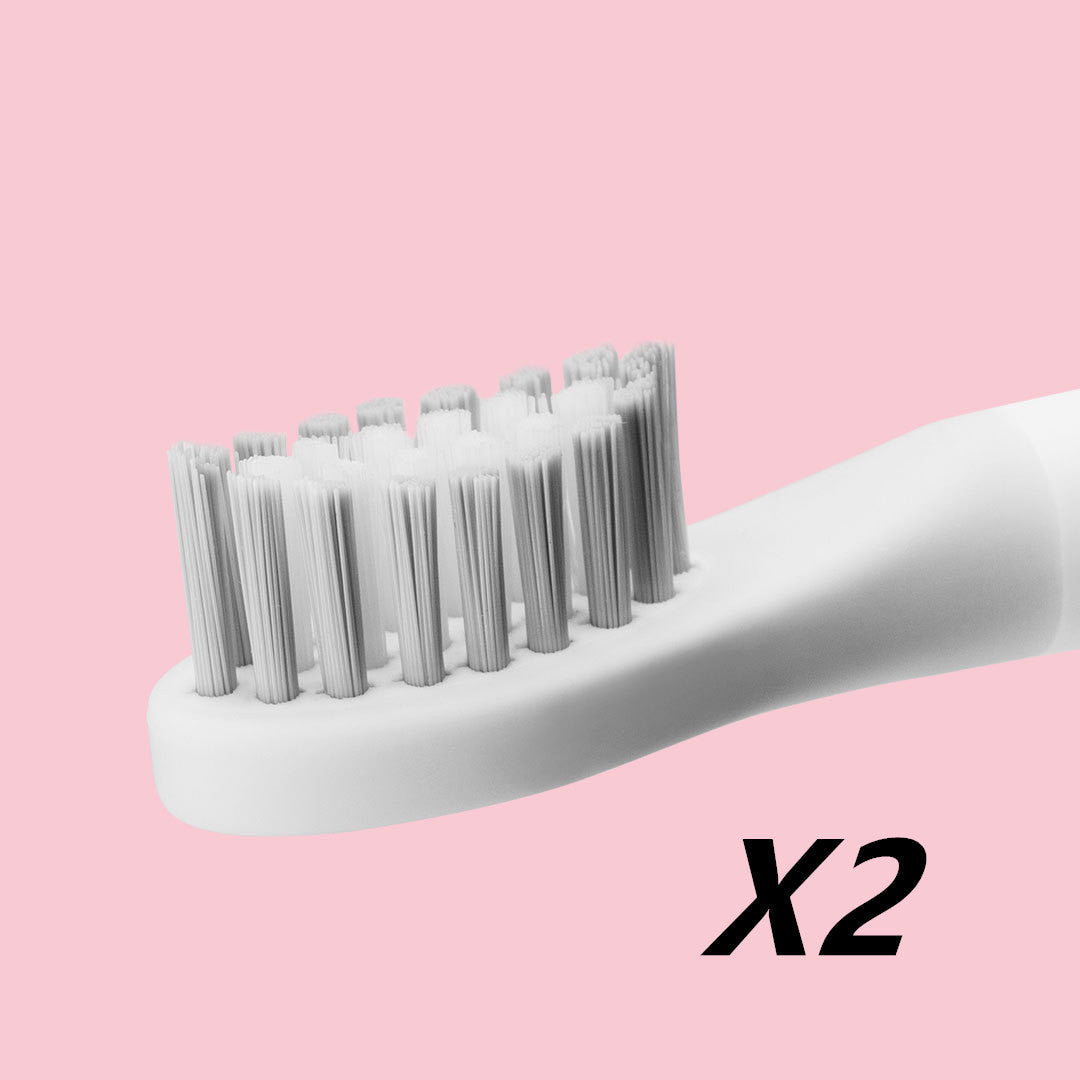 White toothbrush with multiple brush heads on a pink background