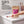A hand is shown placing a white round tablet on a white bathroom counter next to a stand-up pouch of Chomp Junior toothpaste tablets. The scene includes a toothbrush, a tube of toothpaste, and a toothbrush holder in the background, with promotional text on the left.