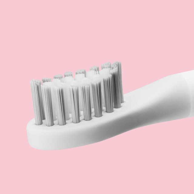 White toothbrush with bristles on a pink background