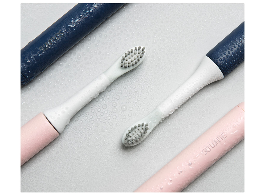 Three electric toothbrushes with different color options on a light gray surface.