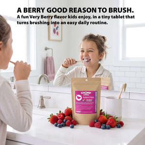A child brushing teeth in a bright bathroom, with a stand-up pouch of CHOMP Chomp Oral Care Super Berry flavor tablets placed on the counter in front of them. Fresh strawberries, blueberries, and other berries are scattered around the pouch, and large promotional text appears at the top of the image.