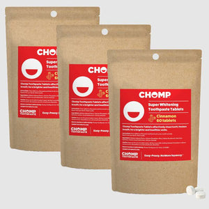 Three packages of CHOMP Super Whitening Toothpaste Tablets on a light gray background