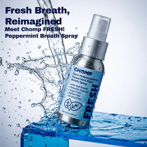Chomp FRESH peppermint breath spray bottle with water splash on a blue background