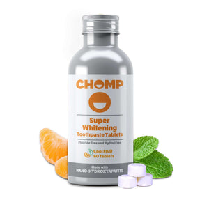 A bottle of CHOMP Super Whitening Toothpaste Tablets, Cool Fruit flavor, shown with orange slices, mint leaves, and three white tablets on a clean white background.
