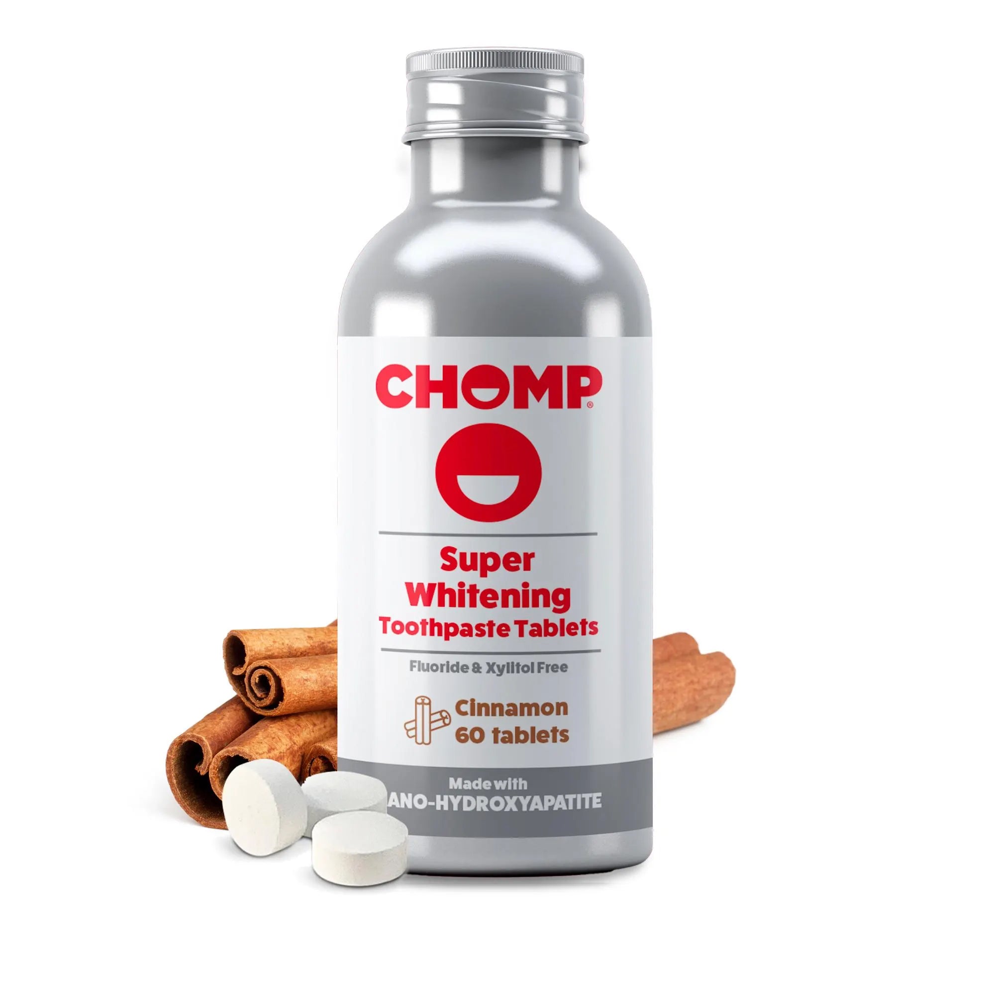 A silver bottle of CHOMP Super Whitening Toothpaste Tablets with cinnamon, shown on a clean white background with several white tablets and cinnamon sticks in front.