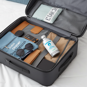 Open suitcase with travel items including a bottle of hand sanitizer, sunglasses, and clothes.