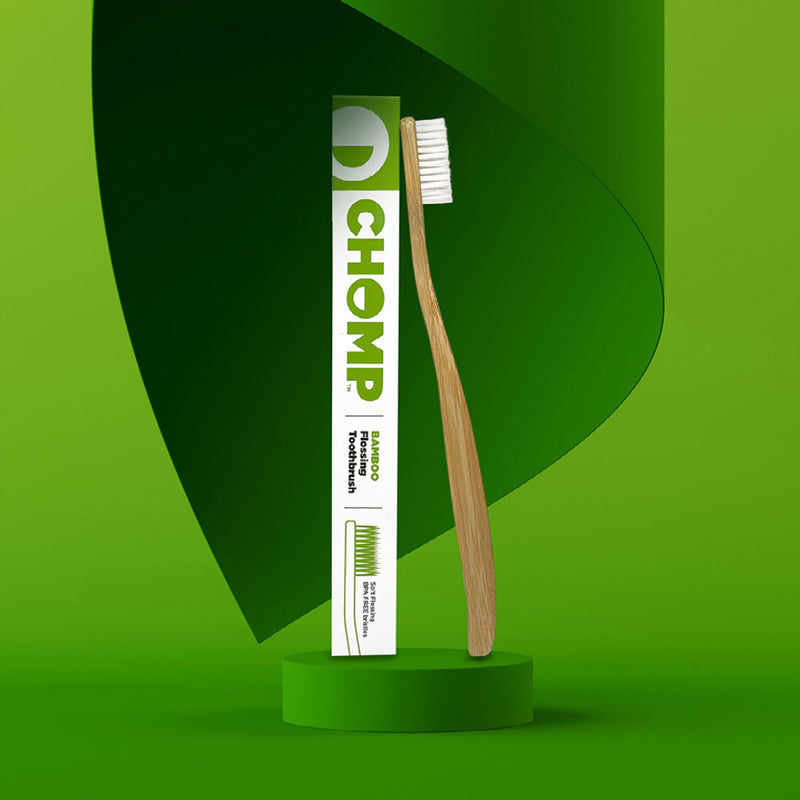 D'CHOMP toothbrush and toothpaste tube on a green background
