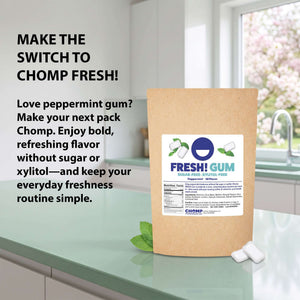 A kraft paper pouch of Fresh! Gum peppermint flavor stands on a kitchen counter with two white gum pieces beside it. Large promotional text on the left reads, 'MAKE THE SWITCH TO CHOMP FRESH!' with supporting copy about bold, sugar-free peppermint gum.
