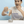 A man in a white t-shirt is shown pouring white tablets from a brown paper pouch labeled 'NanoMints' into a small silver metal container. The background is a solid light blue, with promotional text on the right describing the eco-friendly compostable packaging.