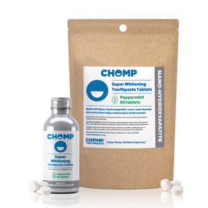 CHOMP Super Whitening Toothpaste Tablets set, featuring a large brown stand-up pouch and a silver bottle, with several white tablets scattered in front on a white background.