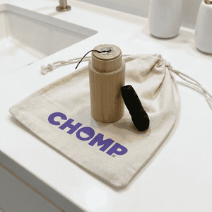 Bathroom counter with a bamboo product and drawstring bag labeled 'CHOMP'.