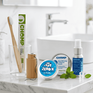 Collection of Chomp dental care products on a marble surface with a blurred bathroom background.