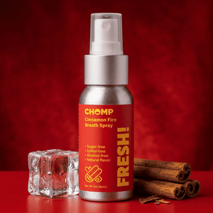 Chomp Cinnamon Fire Breath Spray bottle with cinnamon sticks and ice cube on a red background