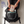 A person kneeling on a light wood floor places a NanoMitts travel pouch into an open black backpack. The scene includes blue text on the left reading 'Travel-Friendly TSA ready and easy for any on-the-go travel.