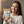 A smiling woman in a cream sweatshirt holds a stand-up pouch of NanoMints natural minty freshness mouth freshener. The background is a soft beige wall with blue promotional text on the left side.