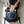 A person kneeling on a light wood floor places a NanoMints travel pouch into an open navy blue backpack. The scene includes text on the left that reads 'Travel-Friendly TSA ready and easy for any on-the-go travel.
