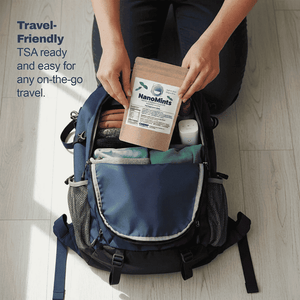 A person kneeling on a light wood floor places a NanoMints travel pouch into an open navy blue backpack. The scene includes text on the left that reads 'Travel-Friendly TSA ready and easy for any on-the-go travel.