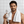 Man holding a bottle of 'Freshe' mouthwash with a towel around his neck in a bathroom setting.