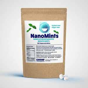 A stand-up kraft paper pouch of NanoMints Breath Mints with a white label, shown on a light gray studio background with two white round mints in front.
