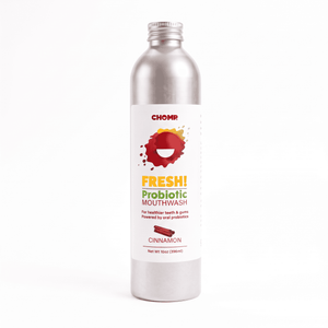 A silver metal bottle of CHOMP Fresh! Probiotic Mouthwash in Cinnamon flavor, featuring a white label with red, yellow, and green text and graphics, set against a plain white background.