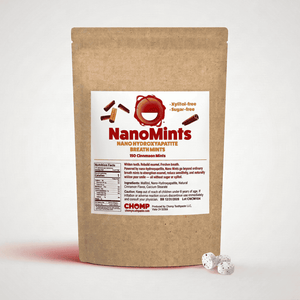 A kraft paper stand-up pouch labeled NanoMints Breath Mints stands on a white background, with three small white speckled mints placed in front of the package.