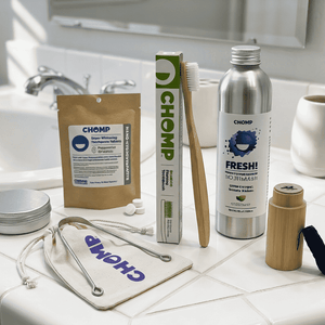 Zero-waste products including a toothbrush, toothpaste, and reusable containers on a bathroom counter.