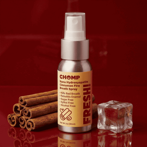 CHOMP breath spray bottle with cinnamon sticks and ice cube on a red background