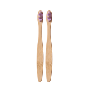 Two bamboo toothbrushes with purple bristles, arranged vertically side-by-side on a light pink background.