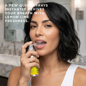 Woman using a breath freshener spray with text about lemon lime freshness in a bathroom setting.
