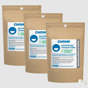 Three packages of CHOMP Super Whitening Toothpaste Tablets on a light gray background
