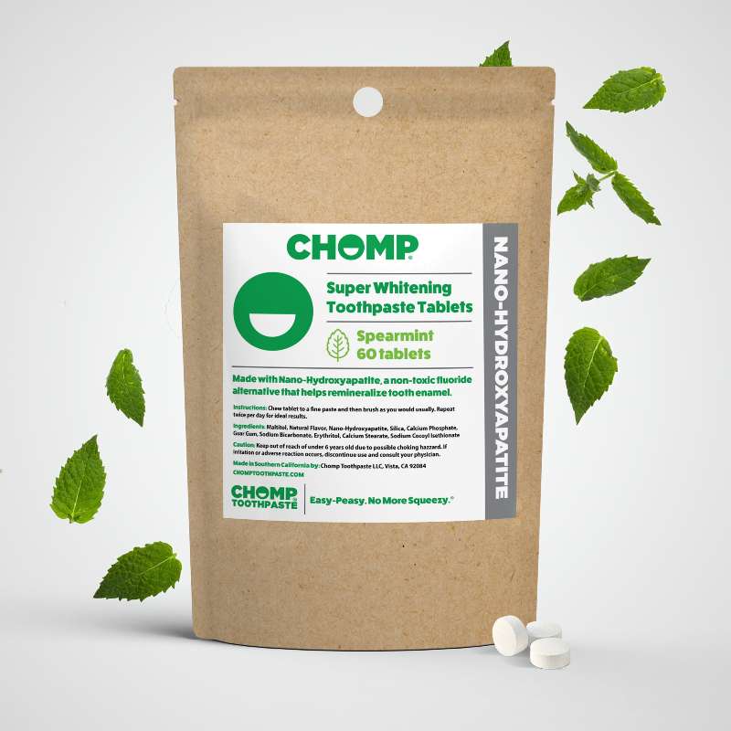 Chomp super whitening toothpaste tablets packaging with spearmint leaves on a light gray background