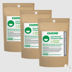Three packages of CHOMP Super Whitening Toothpaste Tablets on a light gray background
