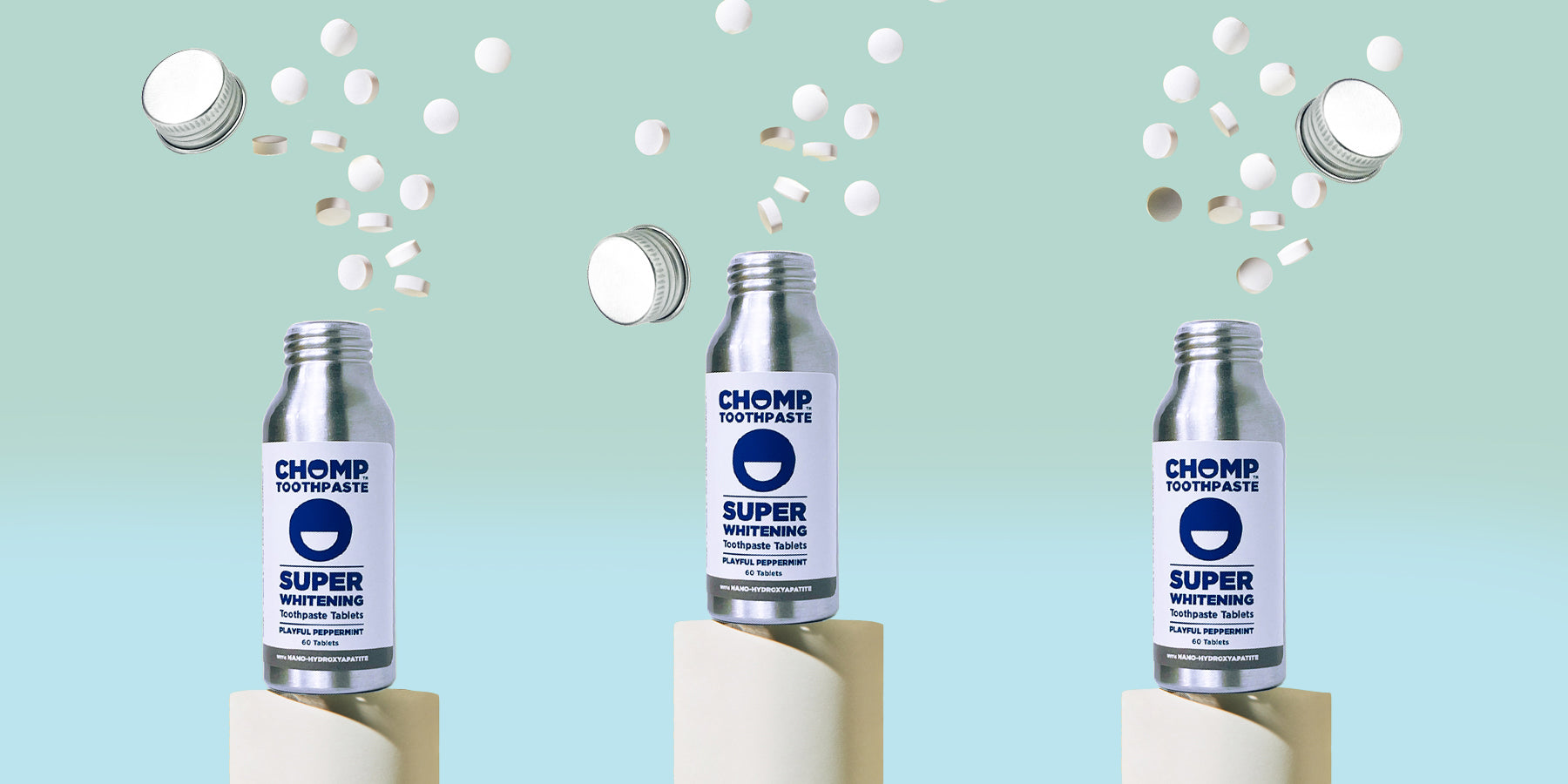 Three bottles of Chomp Super Whitening toothpaste on a light blue background with toothpasteuds.