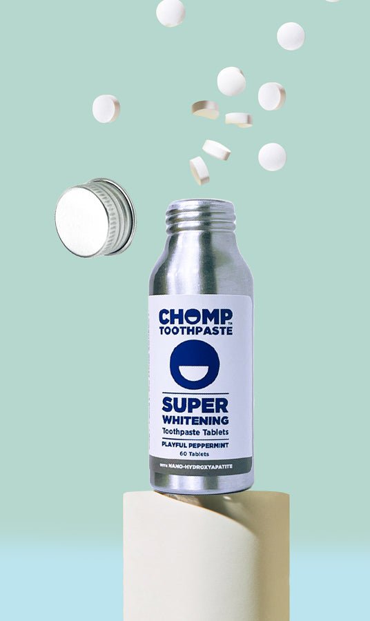 Chomp toothpaste bottle with tablets on a light blue background