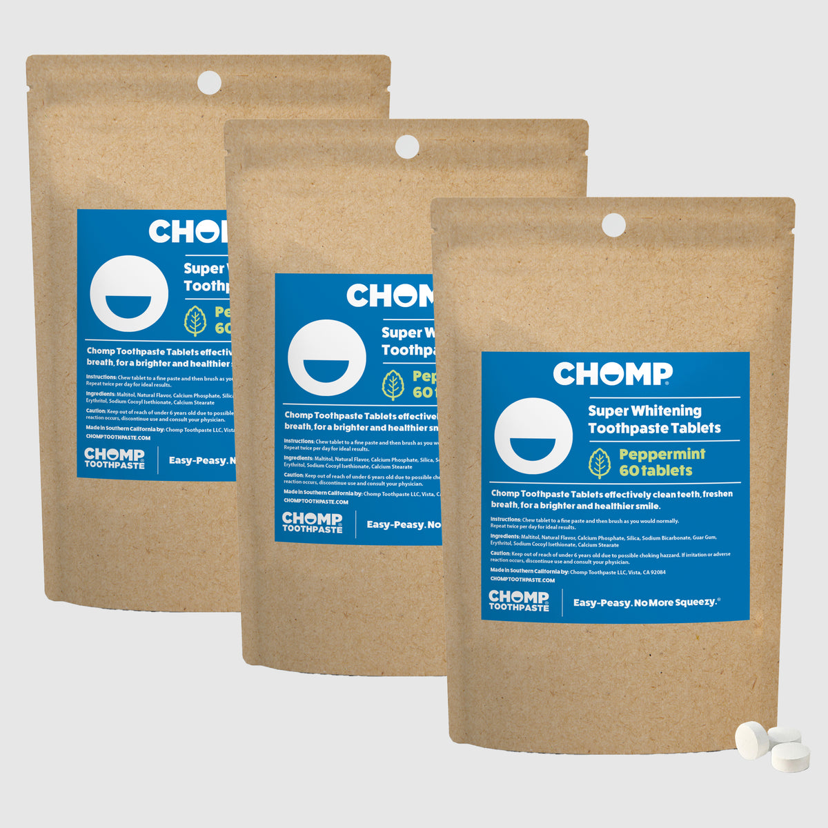 Three packages of CHOMP Super Whitening Toothpaste Tablets on a light gray background