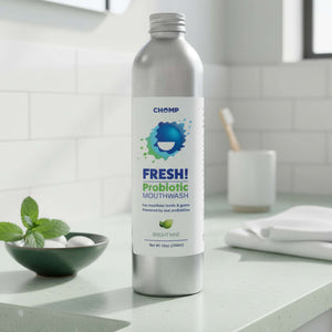 Silver bottle of FRESH! Probiotic Mouthwash on a bathroom counter with a bowl of mint leaves.