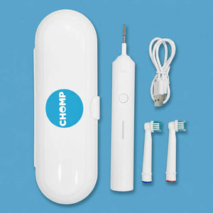 A white electric oral irrigator kit with its carrying case, rechargeable USB charging cable, and two interchangeable brush heads, arranged on a solid blue background. The carrying case features a blue circular logo with the brand name 'CHOMP'.