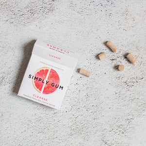 Simply Gum package on a textured surface with loose gum pieces around