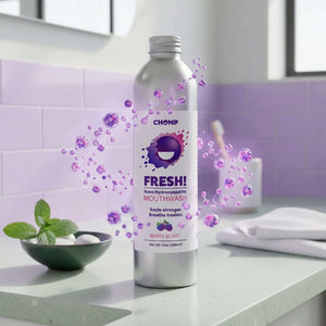 Silver bottle of Chomp Fresh! mouthwash on a bathroom counter with purple bubbles and a purple tiled wall.