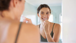 Woman brushing her teeth in front of a mirror