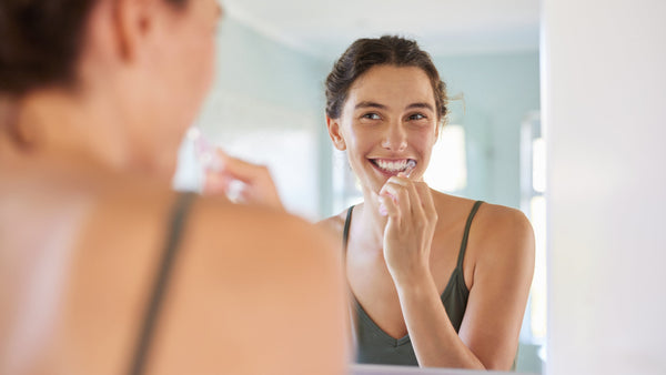 Woman brushing her teeth in front of a mirror